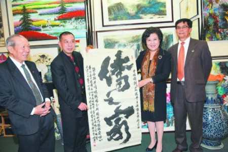 “樂(lè)雅齋”主人、華人書(shū)畫(huà)家鄧作列給裘援平送了“僑之家”書(shū)法作品。(毛建軍 攝)