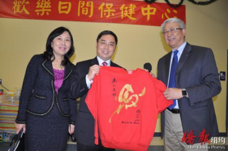 會長李志翔代表活動中心向公使李克新贈送馬年生肖T恤，寓意“馬到成功”（美國《僑報》）