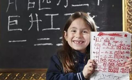 一名外國小學(xué)生拿著滿是漢語學(xué)習(xí)筆記的本子。