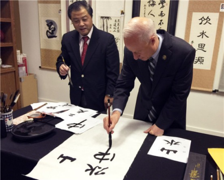 馬克·考夫曼手握毛筆書寫漢字（美國《中美郵報(bào)》）