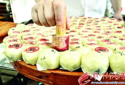 在生餅皮上面綴上黑芝麻，底部墊上白紙片后平整擺放。按傳統(tǒng)慣例，在生餅皮上蓋上鋪號(hào)印章。