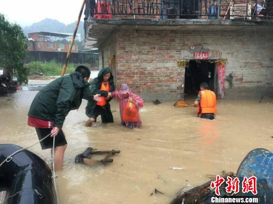在齊大腿深的水中，消防官兵扶著受災(zāi)民眾趟過深水區(qū)。消防供圖