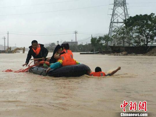 消防官兵利用橡皮艇救助受災(zāi)民眾，由于水中無法前行，官兵跳入水中拉著皮筏前進(jìn)。消防供圖