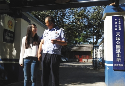 9月19日上午，天壇公園派出所門口，菲菲挽著民警侯祥煒的胳膊。22年前，侯祥煒接群眾報警，從公園南門東側的一棵柏樹下，將被遺棄的菲菲抱回。(圖片來源：新京報)