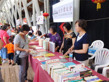 北卡書友會(huì)為游客寫書法和義賣中英文書籍。（美國《世界日報(bào)》/王明心 攝）