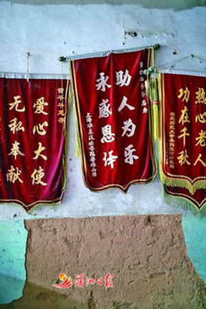 圖為老人家墻上掛滿受助學(xué)生送來的錦旗。