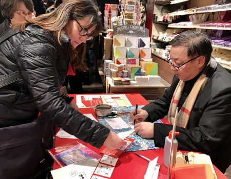 郵票設(shè)計(jì)者、華裔藝術(shù)家李中耀為法國(guó)集郵愛(ài)好者簽名。(法國(guó)《歐洲時(shí)報(bào)》/張新 攝)