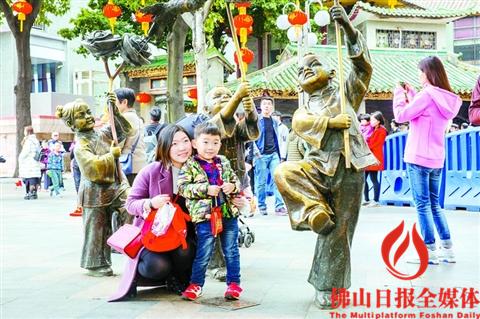 禪城祖廟景區(qū)，一對母子正在景區(qū)門前的雕塑前拍照。/佛山日報記者王澍攝