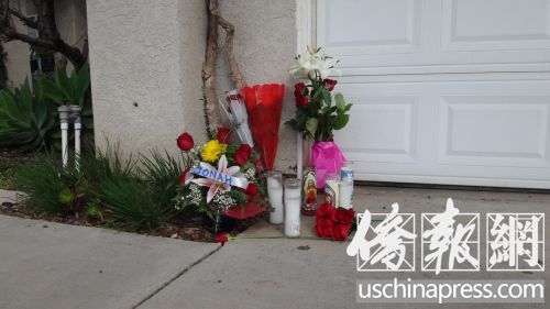 門口擺放著長明燈和鮮花，表達了人們對受害者黃閔的追思和悼念。(美國《僑報》/高睿 攝)