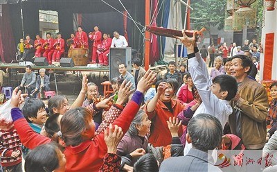 青年男子用托盤端紅豆腐丸，供村民爭搶。