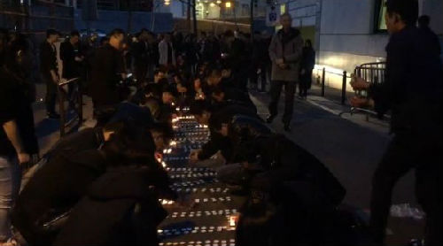 當(dāng)?shù)厝A人擺放蠟燭為死去同胞祈福。(27日晚視頻截圖/韓冰 攝)