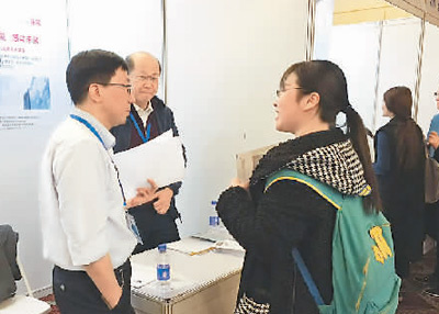 在一家公司的展臺前，一名應(yīng)聘者正在向用人單位咨詢招聘崗位相關(guān)信息。