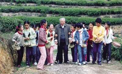 青青茶園里，周大風(fēng)先生和孩子們一邊采茶，一邊唱起了《采茶舞曲》。