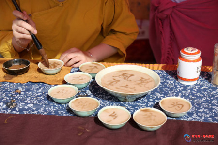 活動(dòng)現(xiàn)場(chǎng)，茶藝人表演茶百戲，在茶沫上用毛筆寫字。