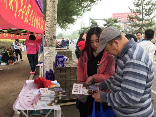 圖為省僑聯(lián)志愿者向考生家長(zhǎng)贈(zèng)閱剛剛印制的《吉林僑聯(lián)》雜志。