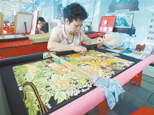 潮繡傳承人李淑英在展示刺繡技藝，她手上的這幅刺繡已經(jīng)繡了將近一年。