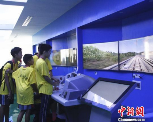 華裔青少年在模擬仿真操作臺上，模擬駕駛高鐵列車?！≈炝?攝