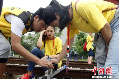 華裔青少年在體驗線路工檢查軌道?！≈炝?攝