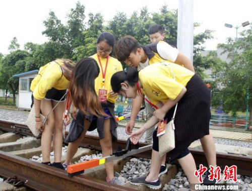 華裔青少年在體驗線路工檢查軌道?！≈炝?攝