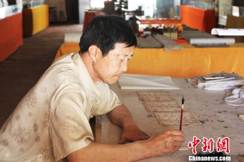 在甘肅敦煌市的一處民俗旅游地——月牙泉小鎮(zhèn)內(nèi)，傅有宏伏案臨摹敦煌漢簡(jiǎn)?！⌒煅?攝