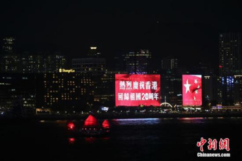 香港回歸祖國二十周年慶典臨近，香港慶回歸氣氛漸濃，6月27日晚，在維多利亞港灣兩側(cè)霓虹閃爍，大廈上的電子屏“升起”巨幅五星紅旗和紫荊花區(qū)旗，交替展現(xiàn)，并有“熱烈慶祝香港回歸祖國20周年”、“祝賀香港回歸20周年”字樣。 <a target='_blank' >中新社</a>記者 盛佳鵬 攝