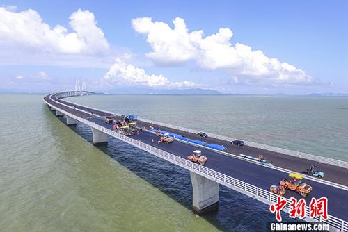 圖為6月8日，工人們?cè)诟壑榘拇髽蛏线M(jìn)行橋面鋪裝。 <a target='_blank' >中新社</a>記者 陳驥旻 攝