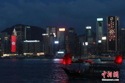 香港回歸祖國二十周年慶典臨近，香港慶回歸氣氛漸濃，6月27日晚，在維多利亞港灣兩側(cè)霓虹閃爍，大廈上的電子屏“升起”巨幅五星紅旗和紫荊花區(qū)旗，交替展現(xiàn)，并有“熱烈慶祝香港回歸祖國20周年”、“祝賀香港回歸20周年”字樣。 <a target='_blank' >中新社</a>記者 盛佳鵬 攝