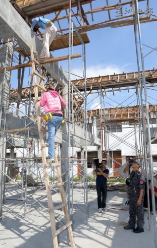 在建筑工地工作的外勞，從建筑中的屋宇樓上爬梯子下樓接受調(diào)查。(馬來西亞《星洲日報》)