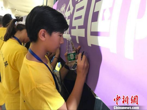 華裔師生在“不忘歷史珍愛和平——南京紫金草國(guó)際和平學(xué)院海外華裔青少年寄語留言”橫幅上簽名。江蘇省僑辦