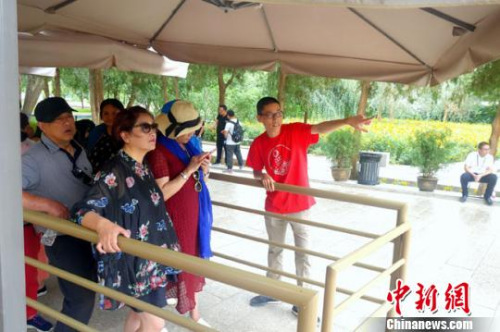 圖為志愿者為等候參觀的游客介紹莫高窟景區(qū)相關(guān)內(nèi)容?！±钗某?攝