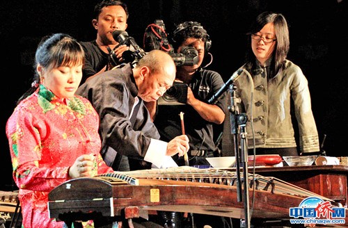 在中印尼宗教交流文藝演出中，作者（左二）和著古箏在寫中國(guó)書法。(圖片均由作者提供)