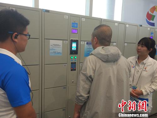 志愿者幫助記者使用電子儲物柜。<a target='_blank'  >中新網</a>記者 李金磊 攝