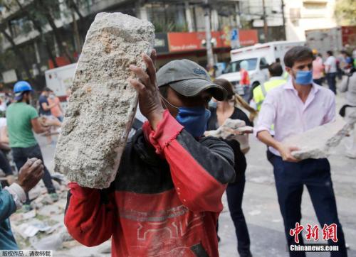 墨西哥城的一處倒塌的建筑廢墟旁，志愿者徒手搬走石塊，以方便救援行動(dòng)展開(kāi)。