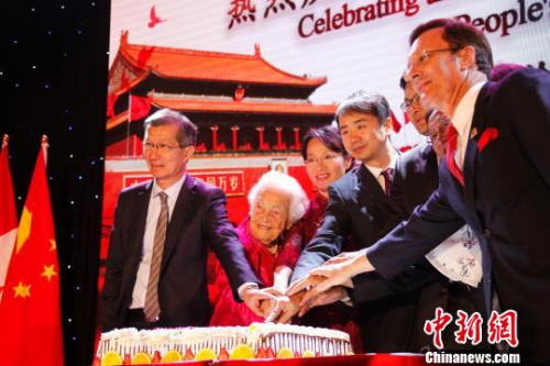 中國(guó)駐多倫多總領(lǐng)事何煒（左四）夫婦、96歲高齡的密西沙加市前市長(zhǎng)麥考蓮（Hazel McCallion，左二）及加拿大各級(jí)政府代表在慶祝中華人民共和國(guó)成立68周年招待會(huì)上共同切蛋糕?！∮嗳鸲z