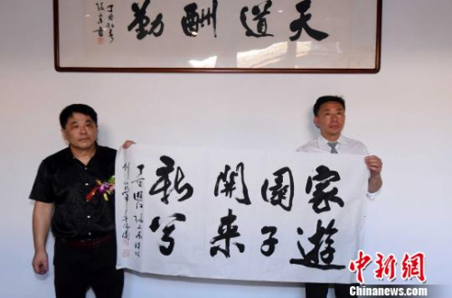 參展書法家美國僑胞游江(右)、張文東(左)現(xiàn)場展示由他們聯(lián)袂揮毫題寫的書法作品。　記者劉可耕 攝