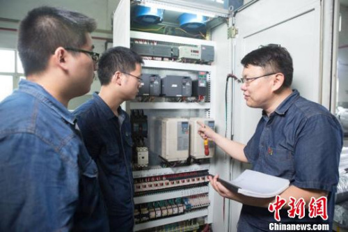 鄧建軍和同事們探討設(shè)備情況。 江蘇常州黑牡丹(集團)股份有限公司供圖。
