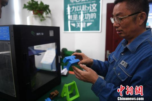 許啟金在工作室中利用3D打印機制作模具。　韓蘇原 攝