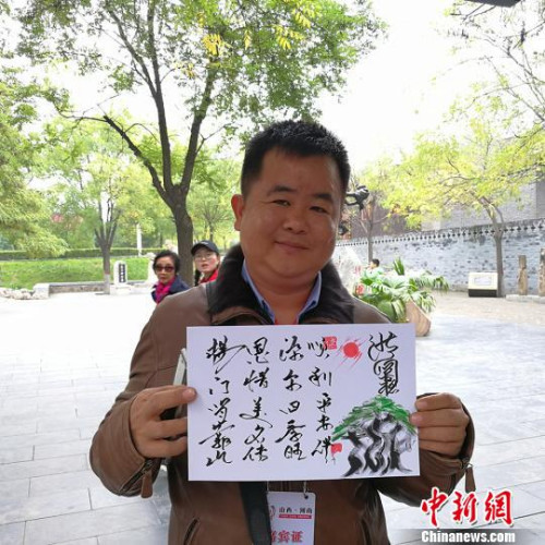 緬甸大其力大華學(xué)校負(fù)責(zé)人楊恩源在洪洞大槐樹景區(qū)向記者展示自己姓氏的文創(chuàng)產(chǎn)品?！罱苡?攝