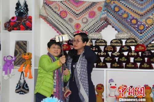 圖為海外華文媒體高層代表在第十二師頭屯河農(nóng)場同和幸福社區(qū)戴著女職工編織的小花帽拍照?！≡?攝