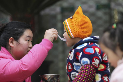 圖3：2015年1月27日，臘八節(jié)，龍灣區(qū)永中街道永中東路一愛(ài)心施粥點(diǎn)，孩子們?cè)诮蚪蛴形镀穱L臘八粥。