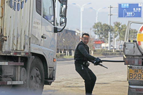 拔槍加油一名男子從油罐車上拔出加油槍，準(zhǔn)備給貨車加油