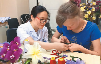 醫(yī)護(hù)人員教俄羅斯患者瑪莎制作手工絲網(wǎng)花。 　　中國(guó)康復(fù)研究中心博愛(ài)醫(yī)院供圖