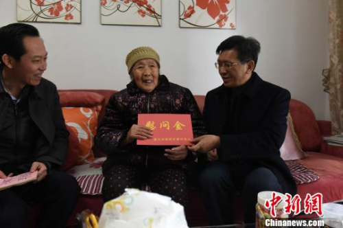圖為重慶市人民政府外事僑務(wù)辦公室黨組書記、主任吳康明向南僑機工遺孀盈明英送上慰問金。　周毅 攝