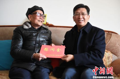 圖為重慶市人民政府外事僑務(wù)辦公室黨組書記、主任吳康明向南僑機(jī)工蔣印生送上慰問金?！≈芤?攝