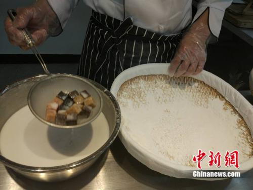 于伯軍將餡料沾上水，準(zhǔn)備投進(jìn)盛滿糯米粉的笸籮內(nèi)搖。<a target='_blank'  >中新網(wǎng)</a> 李金磊 攝