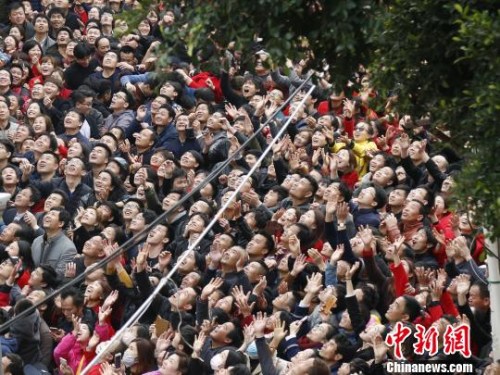 　現(xiàn)場(chǎng)人群高舉雙手，大聲呼喊，奮力接住“僮身”拋來(lái)的銅錢，以求平安、發(fā)財(cái)、好運(yùn)?！×謩俎?攝
