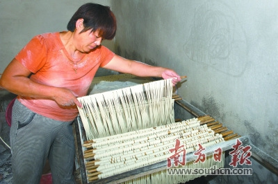 醒面：各握住兩根面桿的一端，將面線往兩邊稍微撐長點(diǎn)，又沾些木茨粉，靜置在面柜上“醒面”。