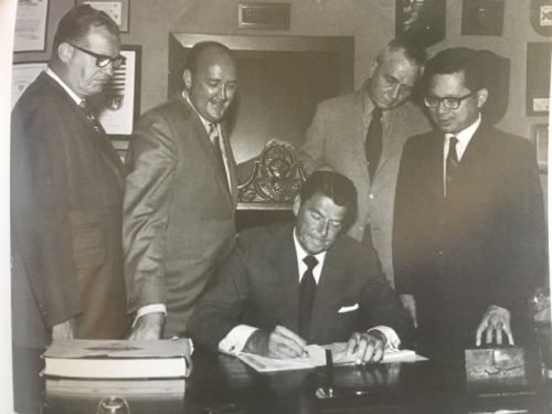 當(dāng)時還是州長的里根(Ronald Reagan)簽署譚卓儀(右一)的“教育補償計劃”提案。(圖片來源：譚卓儀提供)