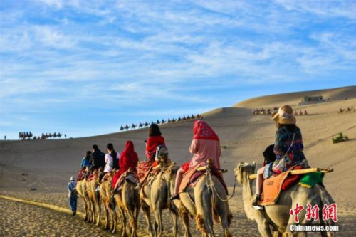 資料圖：絲綢之路國際旅游名城甘肅敦煌，鳴沙山月牙泉人流如織、駝隊如龍。王斌銀 攝