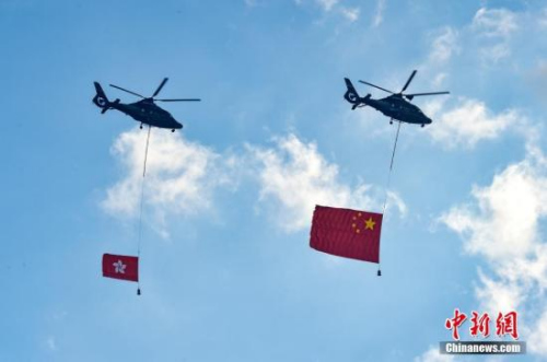 7月1日，香港特別行政區(qū)政府在金紫荊廣場舉行隆重的升旗儀式，慶祝香港回歸21周年。圖為兩架直升機(jī)懸掛五星紅旗和香港區(qū)旗經(jīng)過金紫荊廣場上空。<a target='_blank' >中新社</a>記者 張煒 攝